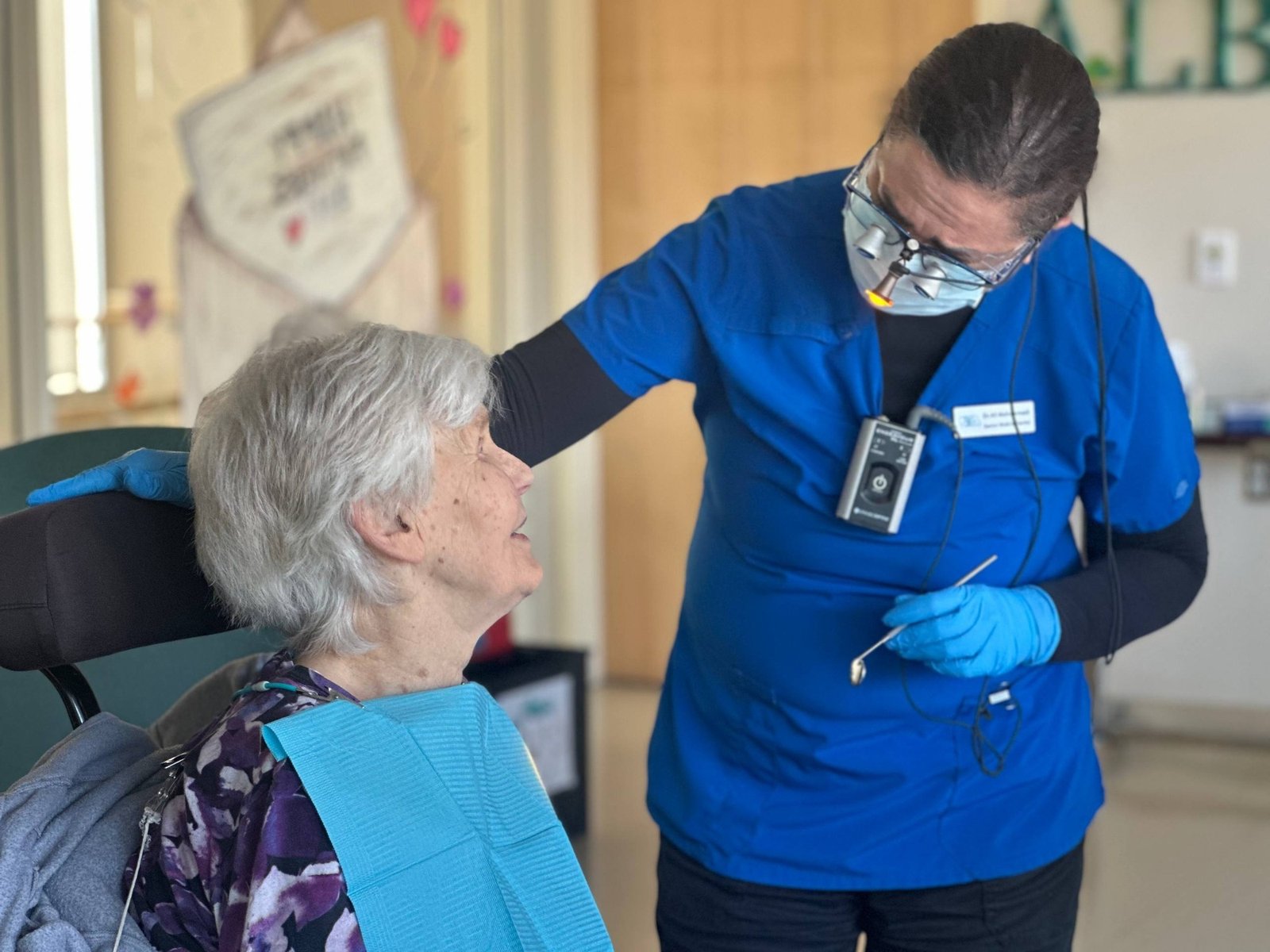 Dental professional conducting a gentle oral assessment for a senior resident in a care setting